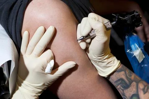 A tattoo artist preparing to tattoo a man's bare arm, close-up Stock Photos