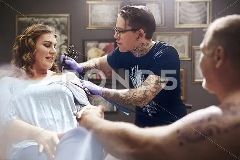 Tattoo artist tattooing woman's shoulder Stock-Fotos