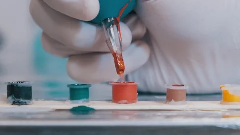Tattoo artist using tattoo gun machine and picking up new color Stock Footage