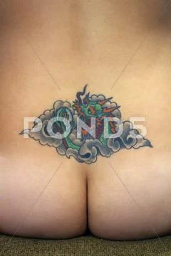 Tattoo on lower back of nude girl Stock Photos