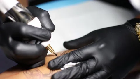 Tattoo machine closeup. Hands of tattoo artist putting lines on skin. Stock Footage 168638682