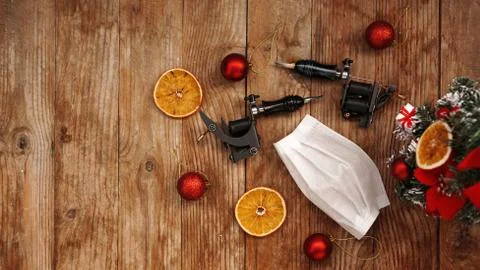 Tattoo machine with protectives face mask on a christmas background Foto stock