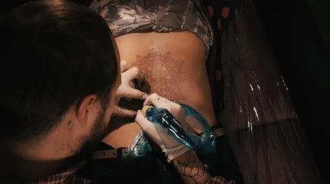 Tattoo master with beard making a tattoo of mandala pattern. Shot from behind Stock Footage 67537968