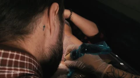 Tattoo master with beard making a tattoo of mandala pattern. Shot from behind Stock Footage 67542606