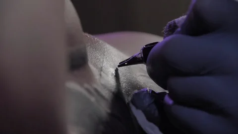 Tattoo master in blue gloves makes a tattoo, macro shot, slowmotion 動画素材 129317070
