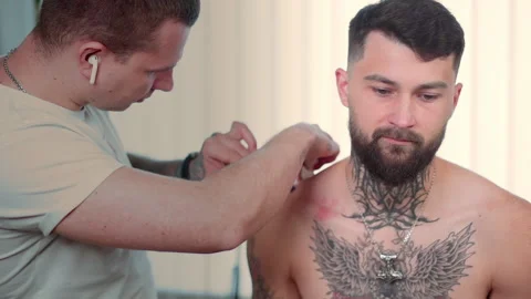 The tattoo master carefully prepares the client's skin for further work with the Stock-Footage 144673113