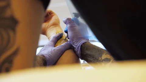 Tattoo master makes a tattoo on his hand client Stock Footage 122294045