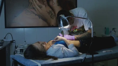 Tattoo master makes the tattoo on a woman's body Stock Footage 73149296
