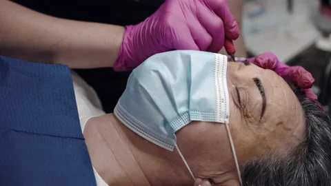 Tattoo master making permanent eyebrows tattoo with color pigment in salon Stock Footage 165409860