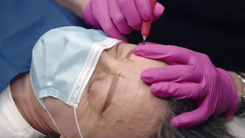 Tattoo master making permanent eyebrows tattoo with colour pigment Stock Footage 170463473