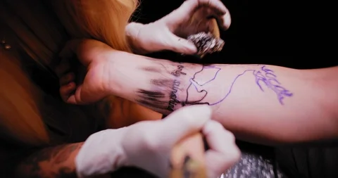 Tattoo master making a tattoo drawing on a person's hand, close up. BMPCC 4K Stock Footage 125764942