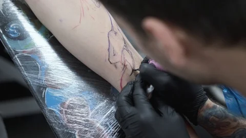 Tattoo Studio, guy gets color tattoo on his arm, it's bleeding Stock Footage 127550824