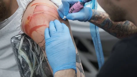 Tattoo Studio, guy gets color tattoo on his arm, it's bleeding Stock Footage 127551486