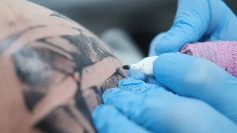 Tattoo Studio, guy gets color tattoo on his arm, it's bleeding Stock Footage 127551707