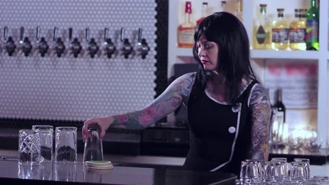 Tattooed bartender lady organizing drinking glasses at the bar Vídeo Stock 82977335