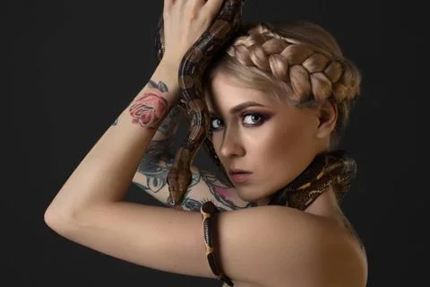 Tattooed blonde with python on gray background Beautiful tattooed blonde w... Stockfoto's