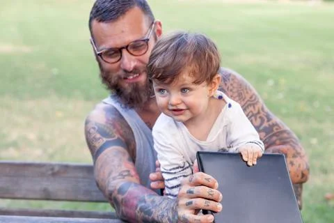 Tattooed dad have fun with his son and laptop Stock Photos