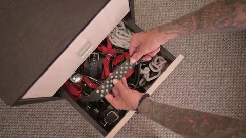 A tattooed hand opens a locker full of adult sexy play sex accessories. Stock Footage 253192564