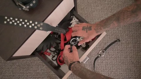 A tattooed hand opens a locker full of adult sexy play sex accessories. Stock Footage 253192618
