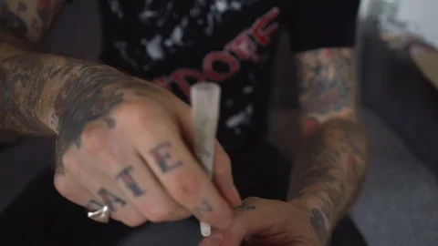 Tattooed hand rolling a marijuana joint Stock Footage 90022981