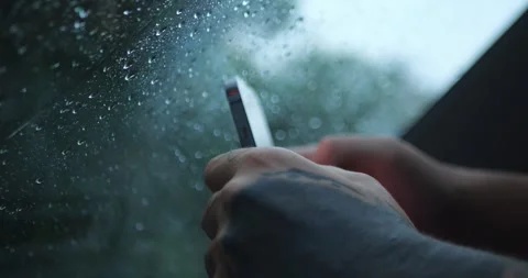 Tattooed Hand Using or Holding Smartphone By Rain-Covered... Stock Footage 332075370