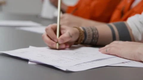 Tattooed Hand Writing on Paper While Inmate Doing Task during Class in Prison Stock Footage 328997463
