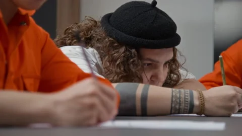 Tattooed Inmate Doing Task Looking Bored and Displeased during Class in Prison Stock Footage 328986732