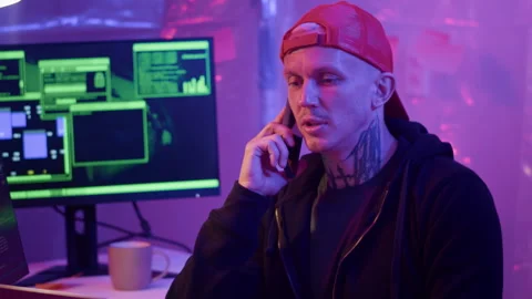 Tattooed Man Hacking and Talking on Phone in Server Room Stock Footage 303561903