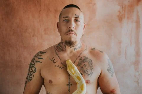 Tattooed man looking at camera with a snake on his chest Stock Photos