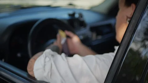 Tattooed man sitting in car using smartphone, scrolling... Stock Footage 324632406