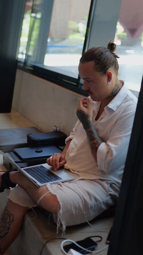 Tattooed man working on laptop in library by window... Vídeo Stock 334437257