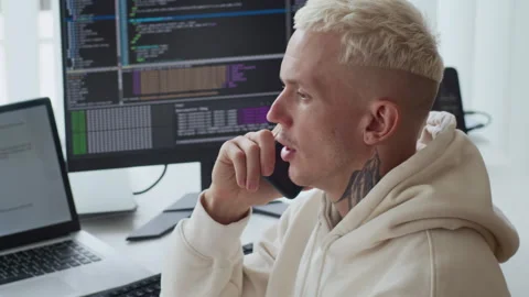 Tattooed Programmer Talking on Phone Working on App Update Stock Footage 303558738