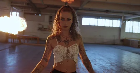Tattooed woman with fire explosion in dramatic movie scene. she walks and is Stock Footage 310728649