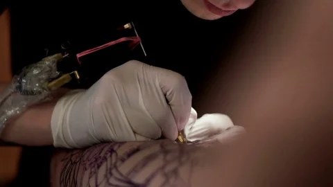 Tattooist does tattoo to a client in a tattoo parlor Stock Footage 76868400