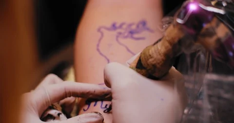Tattooist making a text tattoo drawing on a person's hand. BMPCC 4K Stock Footage 125764975