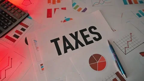Tax documents are spread out on a desk with various charts and graphs present. A Stock Footage 338188327