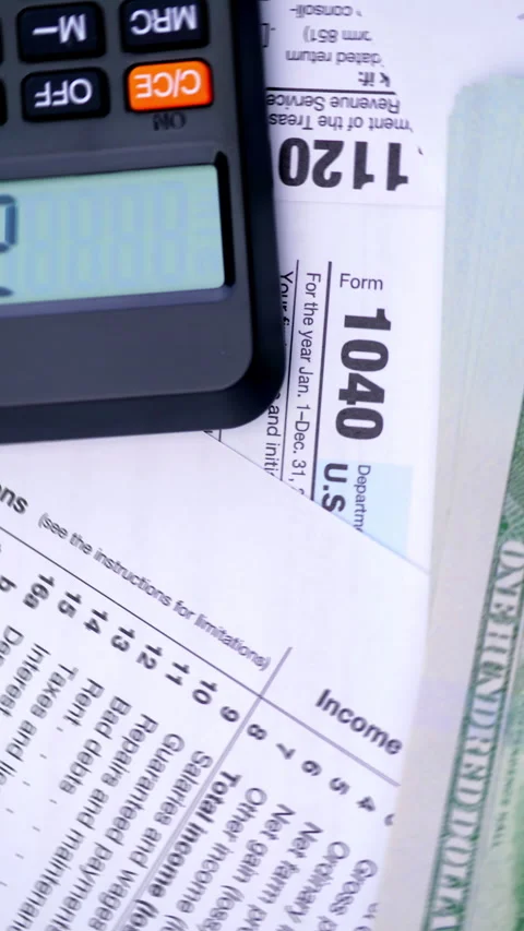 Tax forms, calculator, dollars, and red pen for income tax preparation Stock Footage 344974395