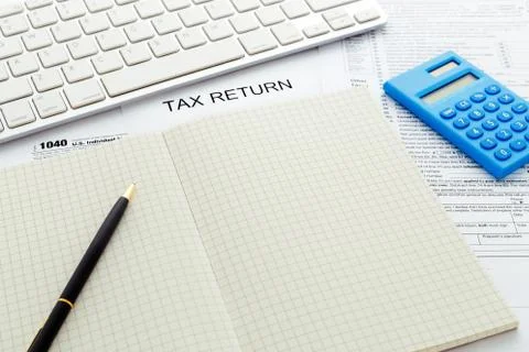 Tax return form with computer keyboard and pen on notebook Stock Photos