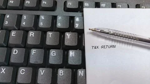 Tax Return written on a note placed on a computer keyboard with a pen Stock Photos