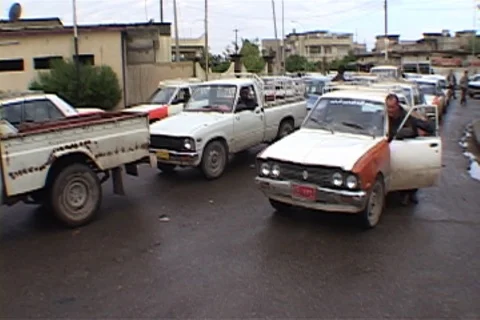 Taxi driver pushes car forward in long gas line, a boy gives him a hand. Stock Footage 86753280