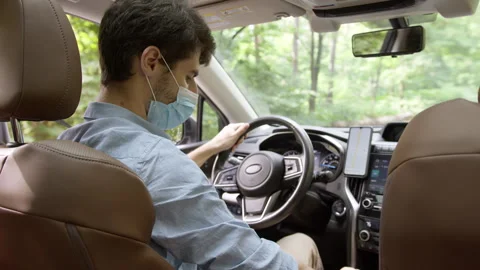 Taxi driver wearing face protective medical mask driving car, finishes the trip  Stock Footage 263165535