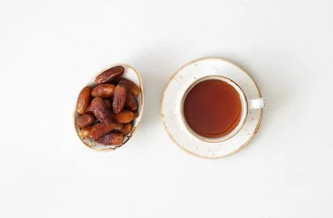 Tea and dried dates on a white background. Natural oriental sweets.  Stock Photos