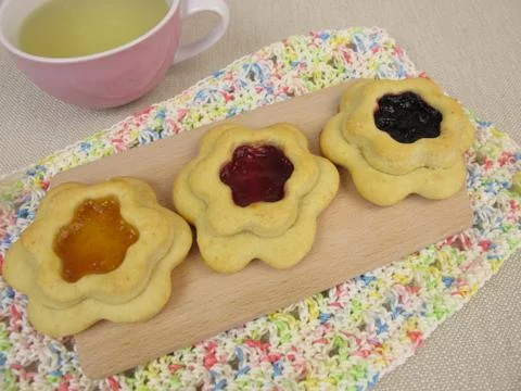 Tea and floret biscuits filled with jam on crocheted doily Stock Photos