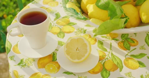 Tea and lemons on a tablecloth with a citrus pattern in daylight. Close-up cup Stock Footage 272534673