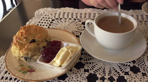 Tea and scones with jam and cream, woman stirs tea in cup Stock Footage 47787779