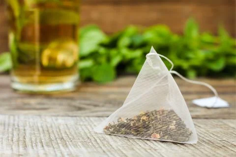 Tea bag on background of mint and and green cup Stock Photos
