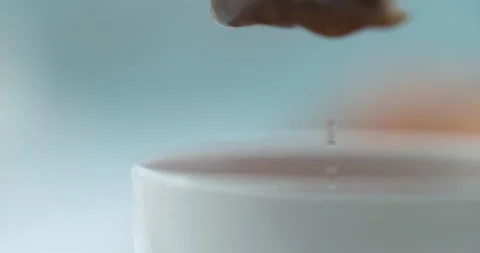 Tea bag being pulled out a white tea cup on a blue background. Close up in slow Stock Footage 199458143