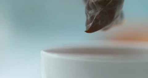 Tea bag being pulled out a white tea cup on a blue background. Close up with a s Stock Footage 199461087