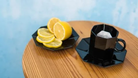 Tea bag in a black cup on a light brown table on a blue cement background Stock Photos