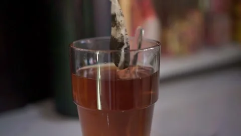 Tea bag brewing in clear glass filled with hot water, Stock Footage 342635294